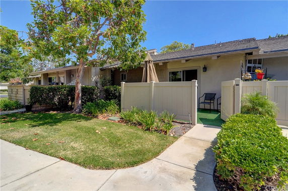 Front view of a single-story house with a small patio and fenced yard.
