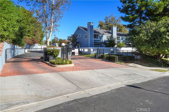 Front view of a two-story house with a gated driveway and chimney.