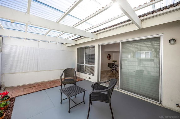 Covered patio area with seating under a transparent roof.