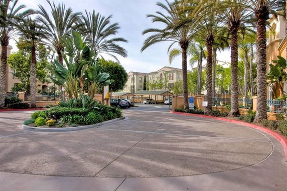 View of a residential building complex with palm trees and a parking area.