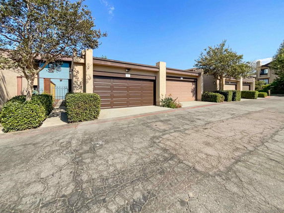 Front view of a building with multiple garage doors and a concrete driveway.