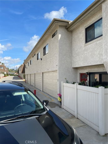 Side view of a residential building with a row of garages and white picket fencing.
