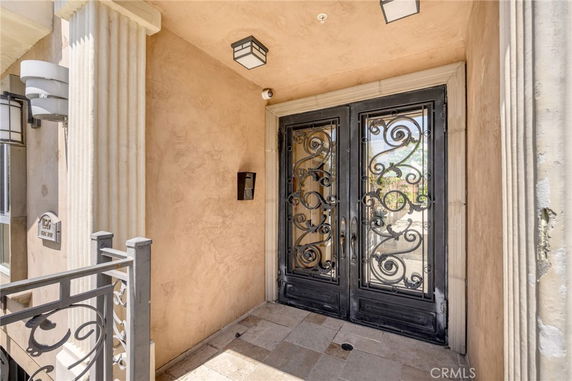 Front view of a building entrance with decorative iron double doors and stone columns.