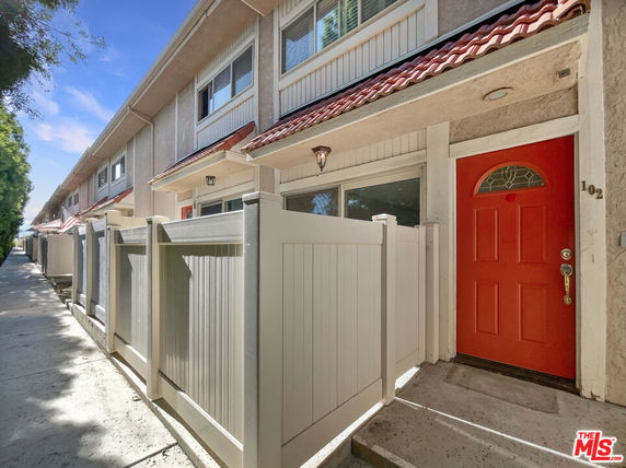 Front view of a two-story townhouse with a red door and fenced entryway.
