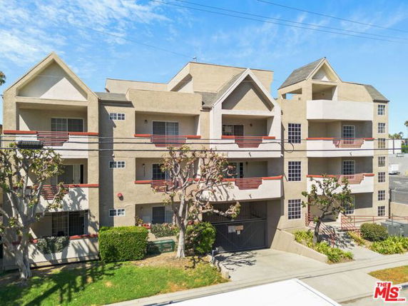 Front view of a multi-story apartment building with balconies and gabled roofs.