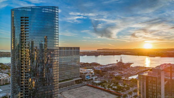 View of high-rise buildings with a waterfront and sunset in the background.