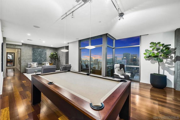 Indoor recreation area with a pool table, seating, and large windows showing a cityscape.
