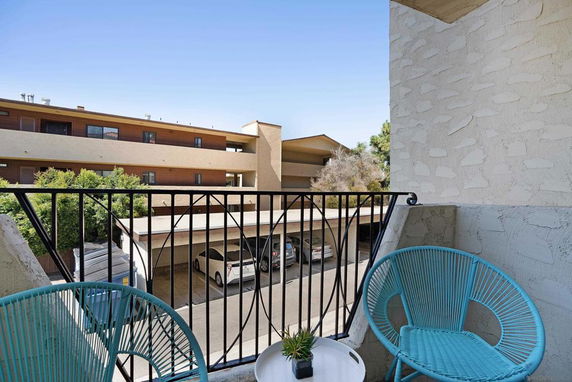 View from a balcony overlooking a parking area and neighboring buildings.