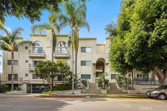 Front view of a multi-story residential building with balconies and arched entrance.