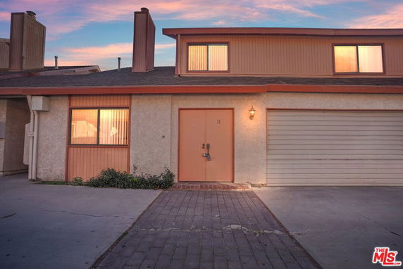 Front view of a two-story house with an attached garage and a paved driveway.