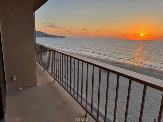 View of the ocean from a building balcony at sunset.