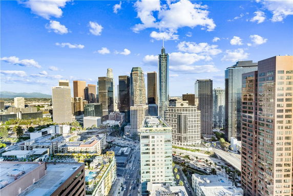 Panoramic cityscape view with numerous skyscrapers under a blue sky with clouds.