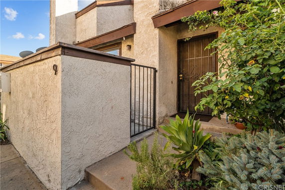 Front view of a house entrance with steps and a metal gate.