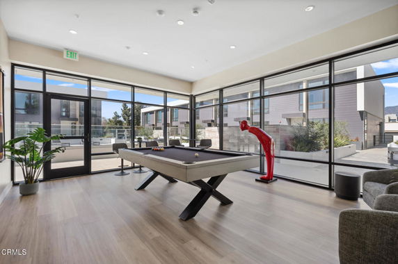 Room with large windows featuring a pool table and modern seating.