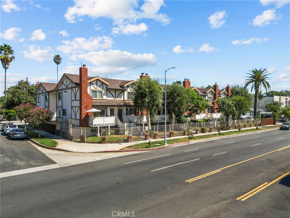 Front view of a multi-story residential building with chimney structures and fencing.