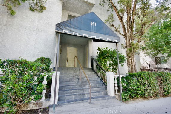 Front view of a building entrance with a black awning and stairs.
