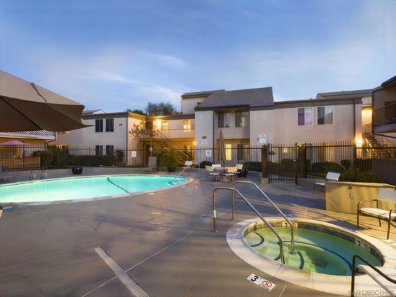 Outdoor area featuring a swimming pool and hot tub in front of a multi-story building.