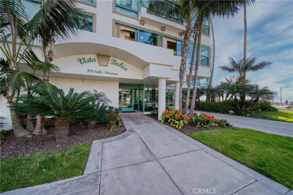 Front view of a multi-story building entrance with palm trees and landscaped area.