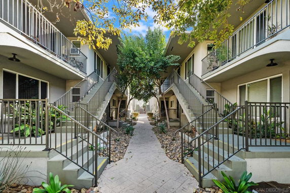 View of apartment buildings with staircases leading to upper floors and a central pathway.