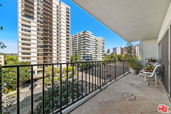 View from a high-rise apartment balcony overlooking nearby buildings and street.