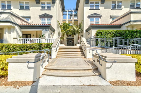 Front view of a multi-story building with a central staircase and landscaped entry.