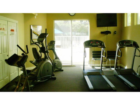 Room with exercise equipment including treadmills and elliptical machines.