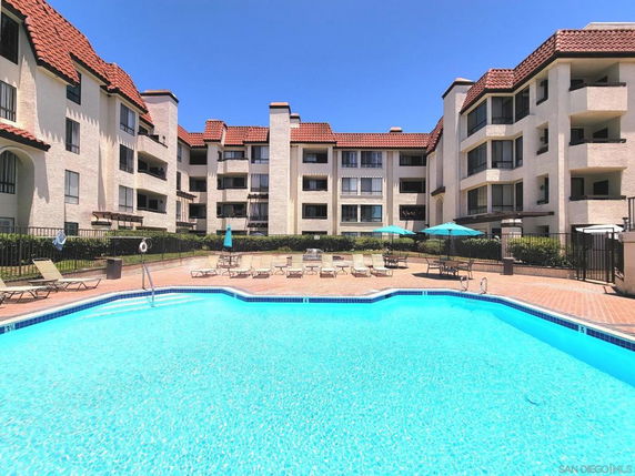 Outdoor view of a multi-story residential building with a swimming pool in front.