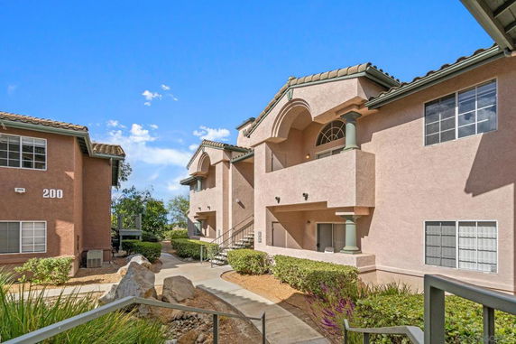 Front view of a multifamily building with stucco exterior and tiled roof.