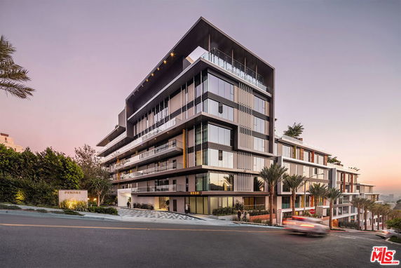 Front view of a modern multi-story building with glass balconies and sleek design.