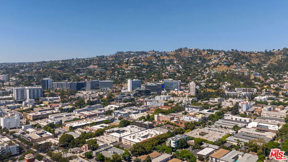 Aerial panoramic view of an urban area with multiple buildings and surrounding hills.