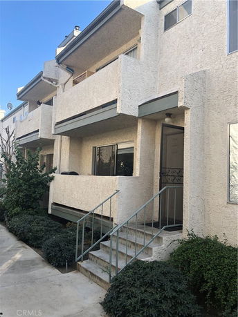 Front view of a two-story building with balconies and stairs.