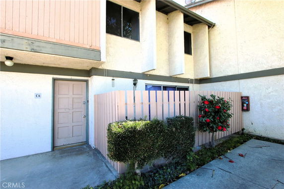Front view of a two-story building with a gated entrance and small garden area.