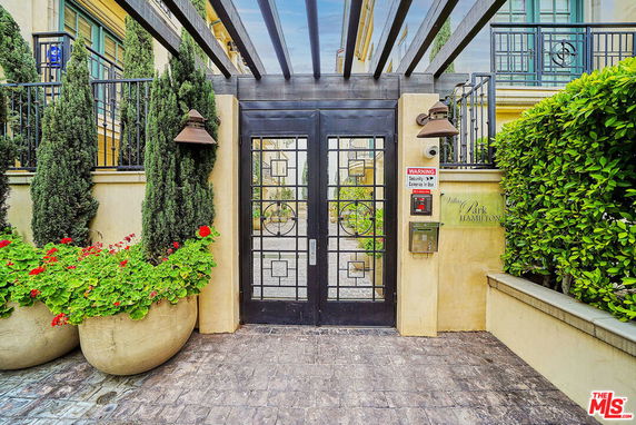 Entrance gate to a modern building with potted plants and security features.
