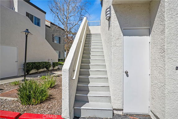 View of an exterior stairway leading to a flat-roofed building with textured walls.