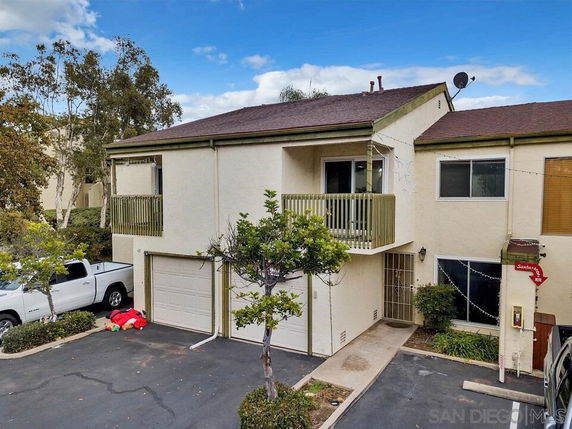 Front view of a two-story townhouse with a balcony and attached garage.