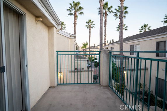 Balcony view over a residential area with palm trees and neighboring buildings.