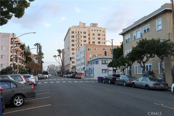 Street view with several multi-story buildings and parked cars.