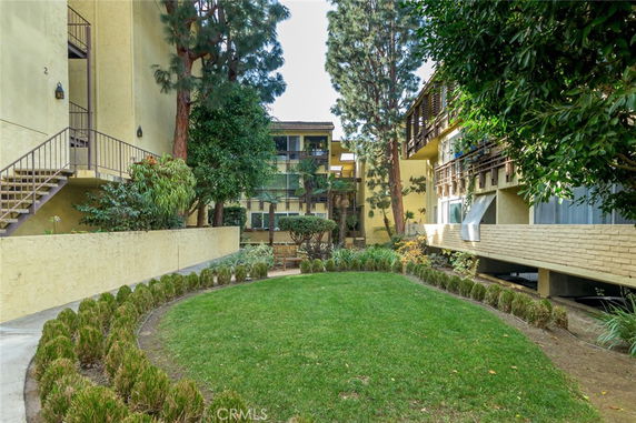 View of an apartment building with balconies, surrounded by trees and greenery.