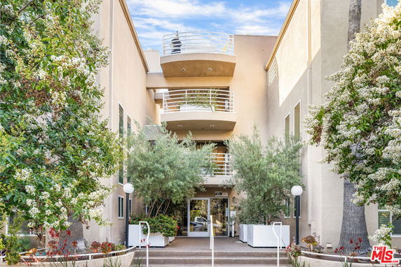 Front view of a multi-story building with balconies and glass entrance.