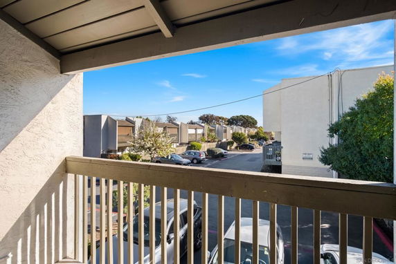 View from a balcony showing a parking area and residential buildings in the background.