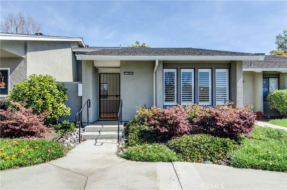 Front view of a single-story house with gray walls and white window shutters.