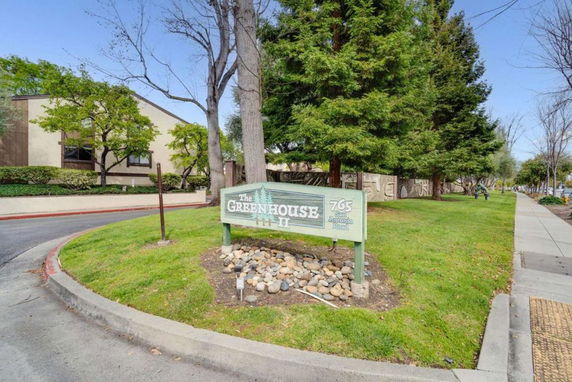 Front view of a building labeled 'The Greenhouse II' with a surrounding green area and trees.