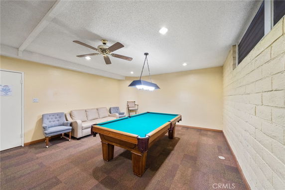 Room with a billiards table, ceiling fan, and seating area.