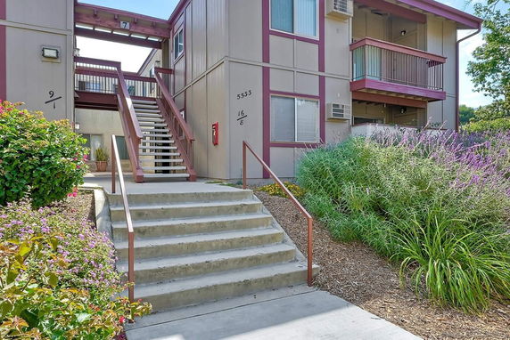 Front view of a multi-level apartment building with stairs and balcony.