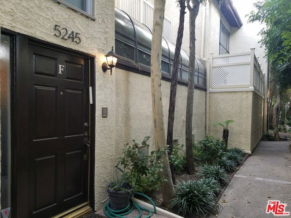 Front view of a two-story building with an entrance and plant-lined pathway.