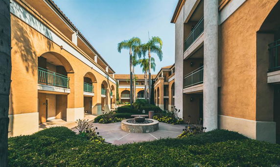 View of a courtyard area in a multi-story residential building with arches and balconies.
