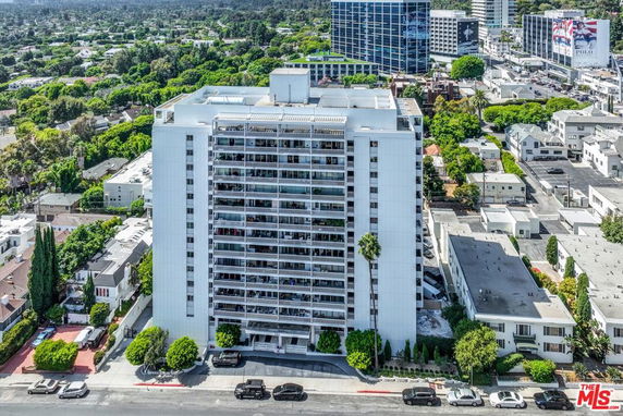 Front view of a tall building with multiple balconies in an urban area.