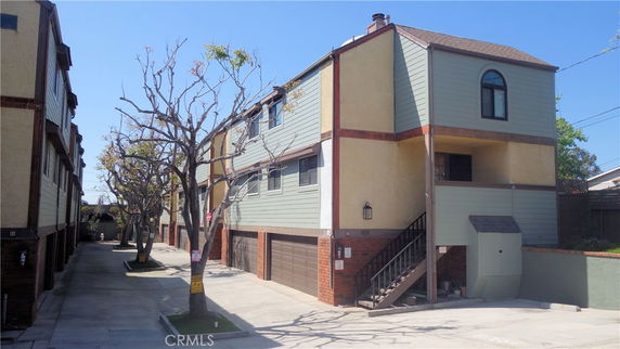 Front view of a multi-story building with a staircase and garage.