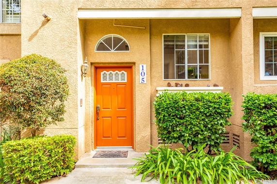 Front view of a house with an orange door and beige exterior walls.