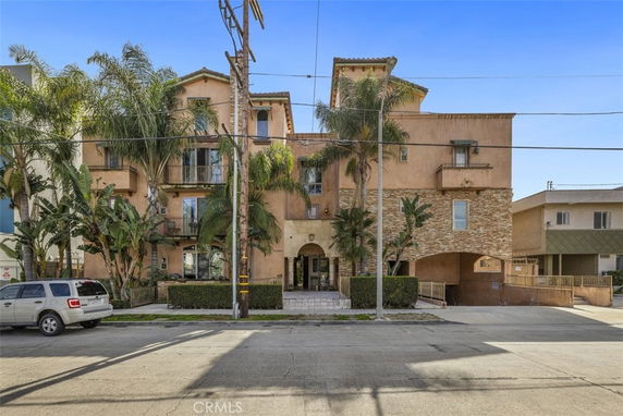 Front view of a multi-story residential building with balconies and archway entrance.